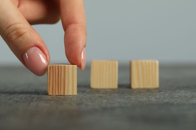 Photo of Woman with wooden cubes at grey table, closeup