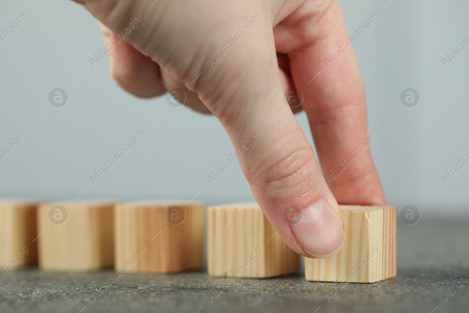 Photo of Woman with wooden cubes at grey table, closeup