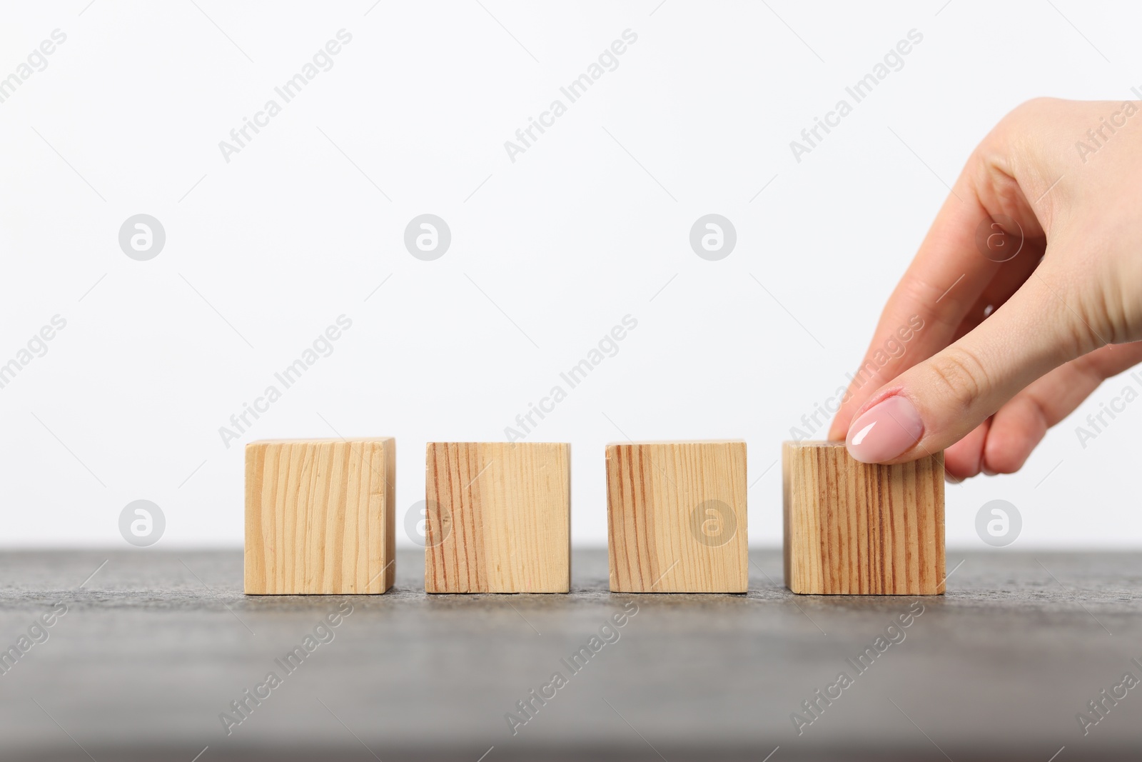 Photo of Woman with wooden cubes at grey table, closeup