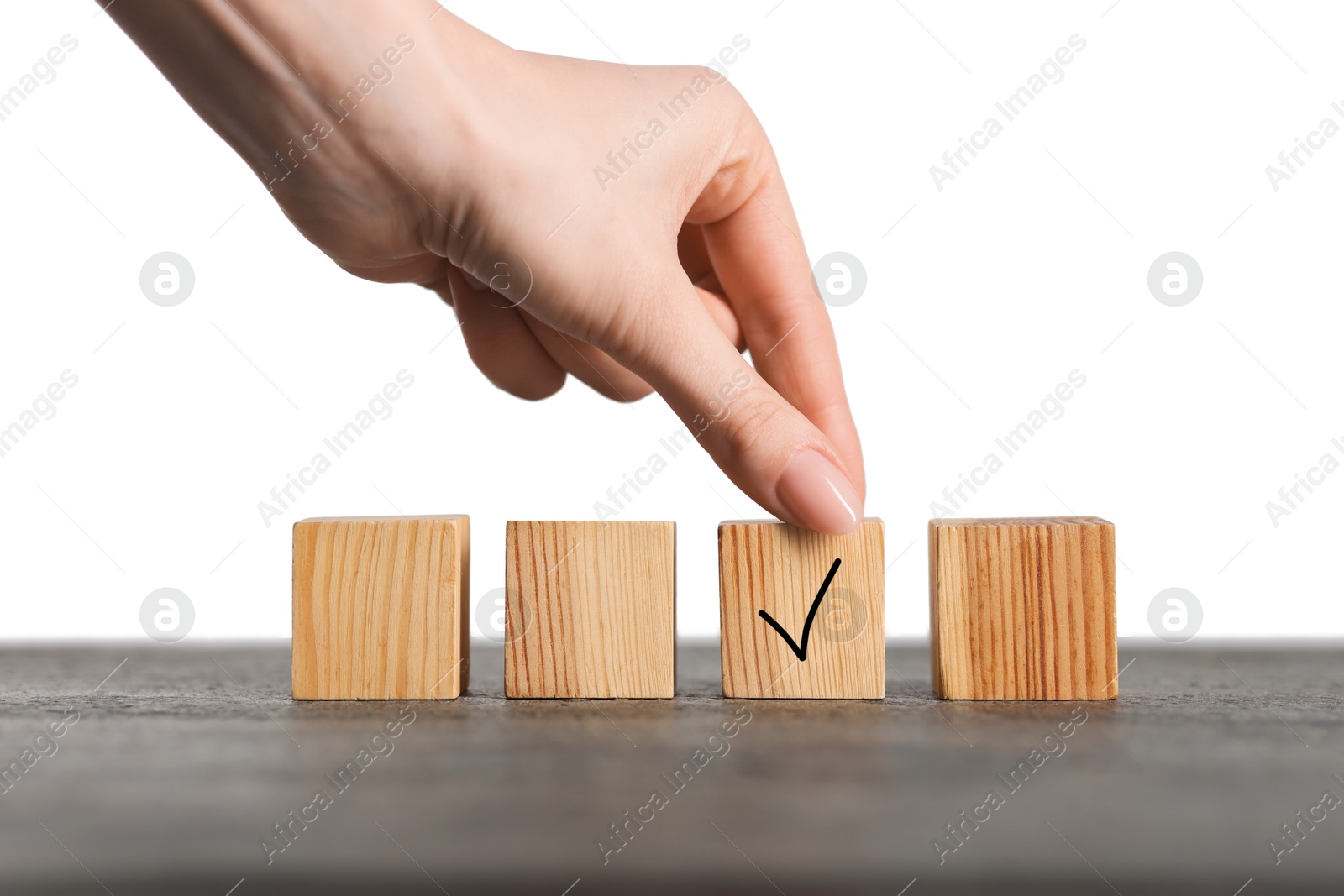 Photo of Woman taking wooden cube with check mark at grey table, closeup