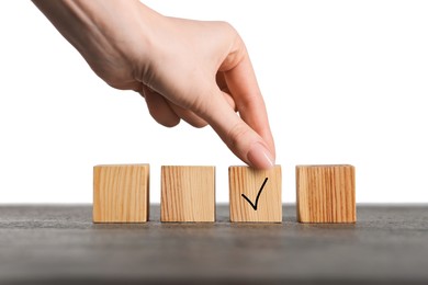 Photo of Woman taking wooden cube with check mark at grey table, closeup