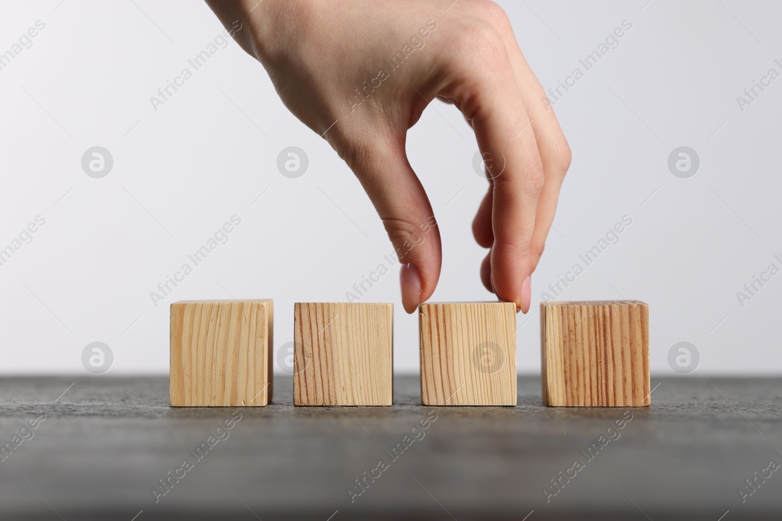 Photo of Woman with wooden cubes at grey table, closeup