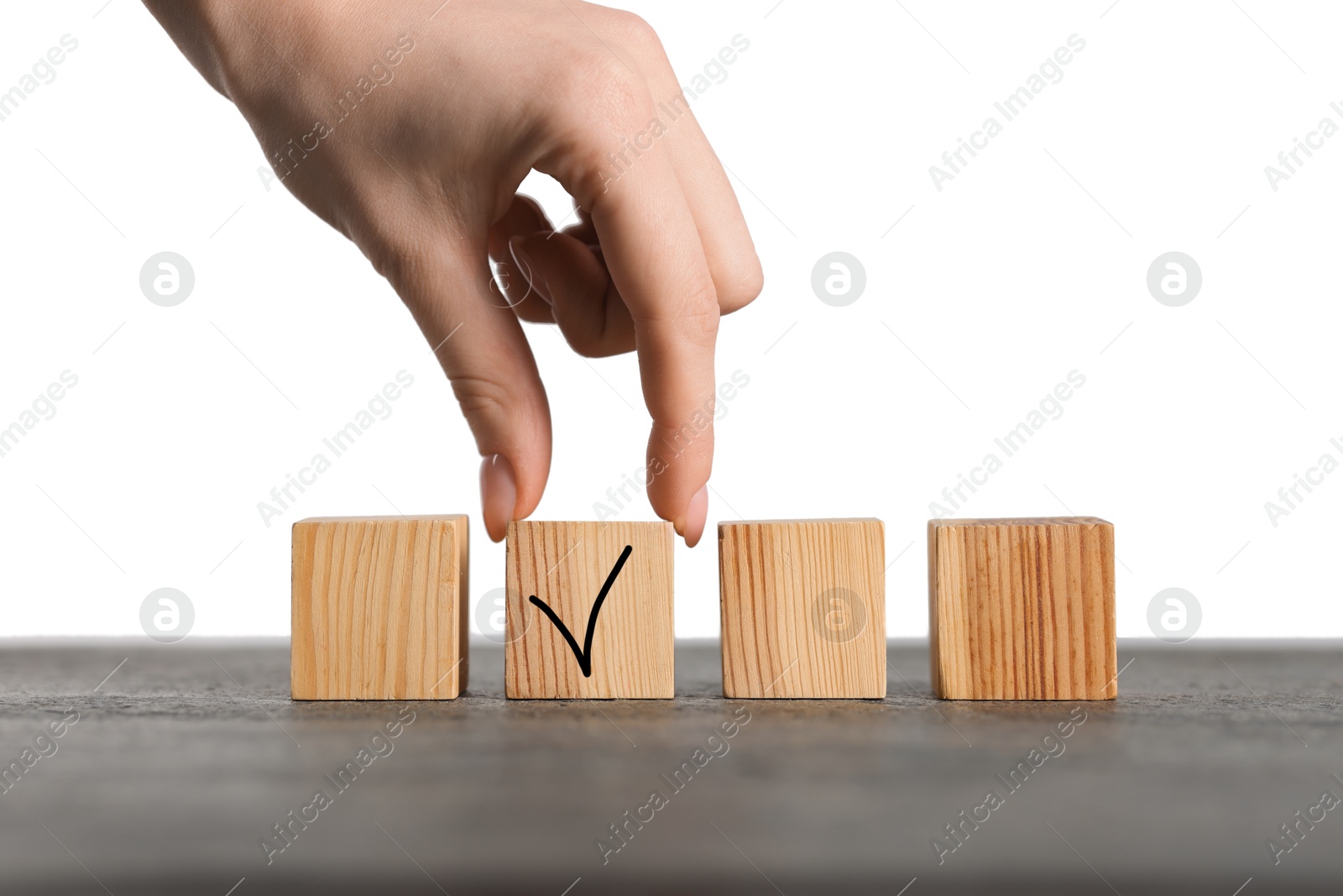 Photo of Woman taking wooden cube with check mark at grey table, closeup