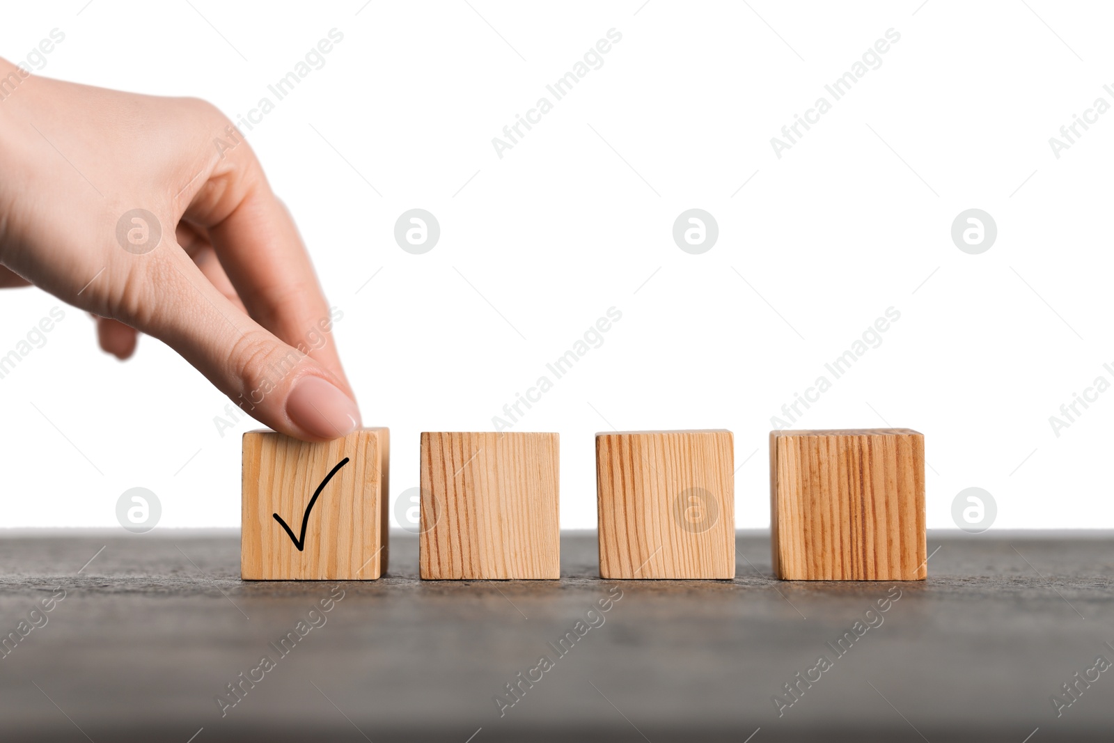 Photo of Woman taking wooden cube with check mark at grey table, closeup