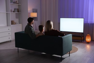 Happy family watching tv together at home in evening