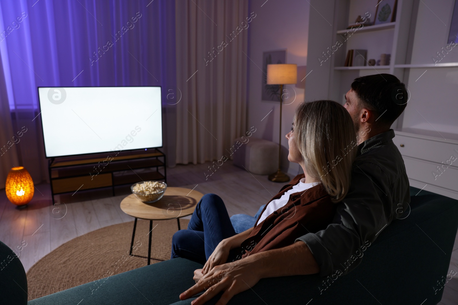 Photo of Lovely couple watching tv at home in evening