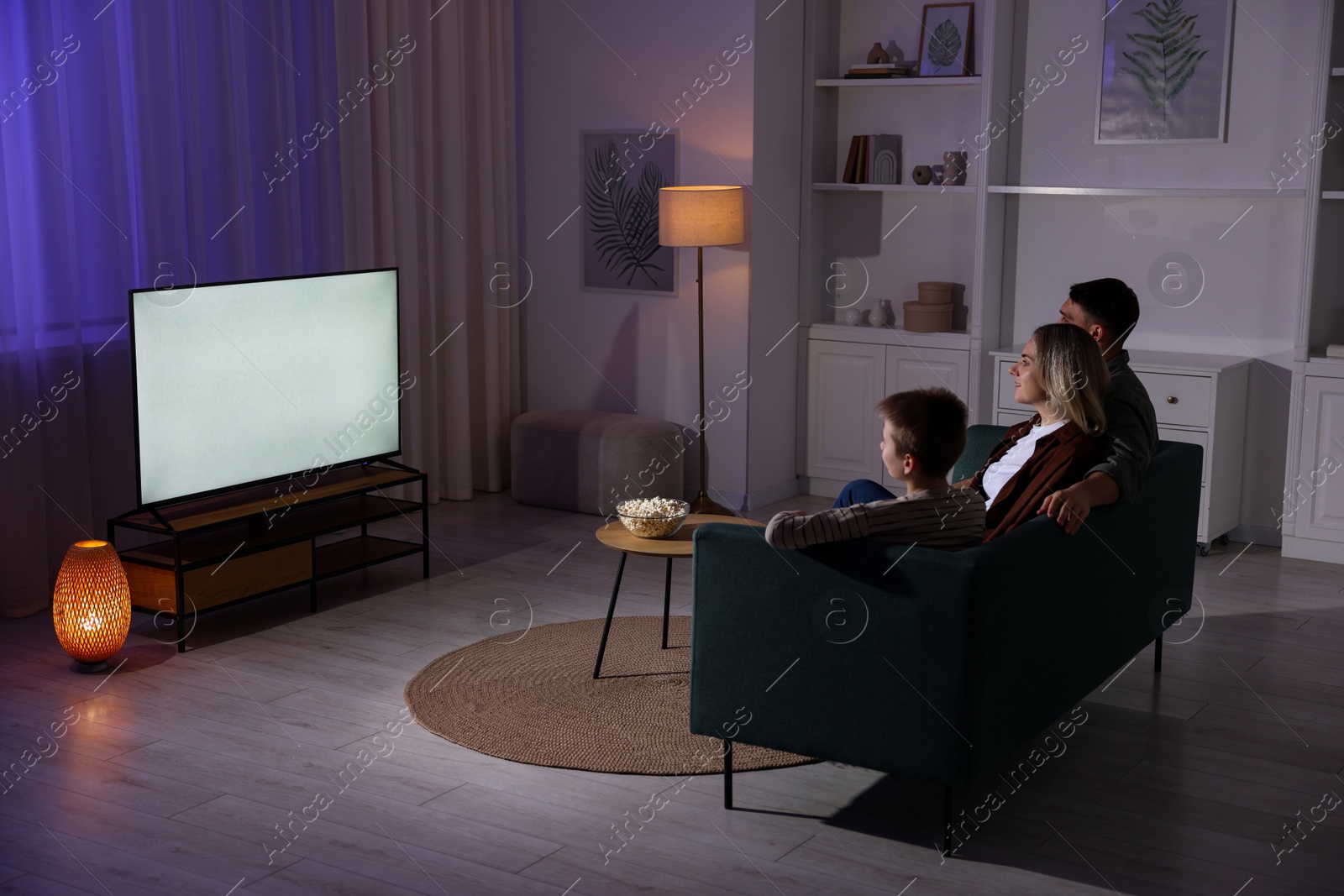 Photo of Happy family watching tv together at home in evening