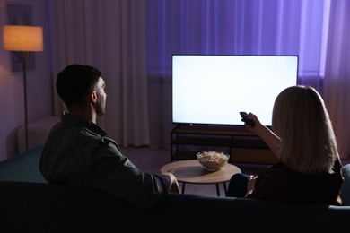 Photo of Lovely couple watching tv at home in evening, back view