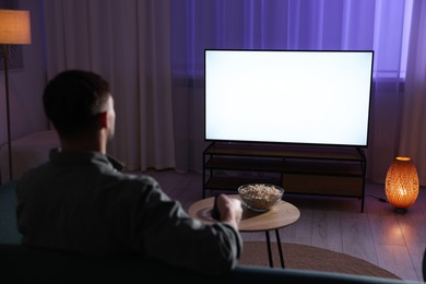 Photo of Man watching tv at home in evening, back view