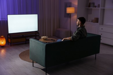 Man watching tv at home in evening