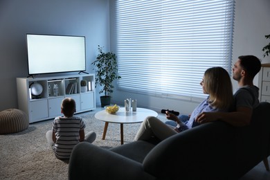 Photo of Happy family with snacks and drinks watching tv together at home