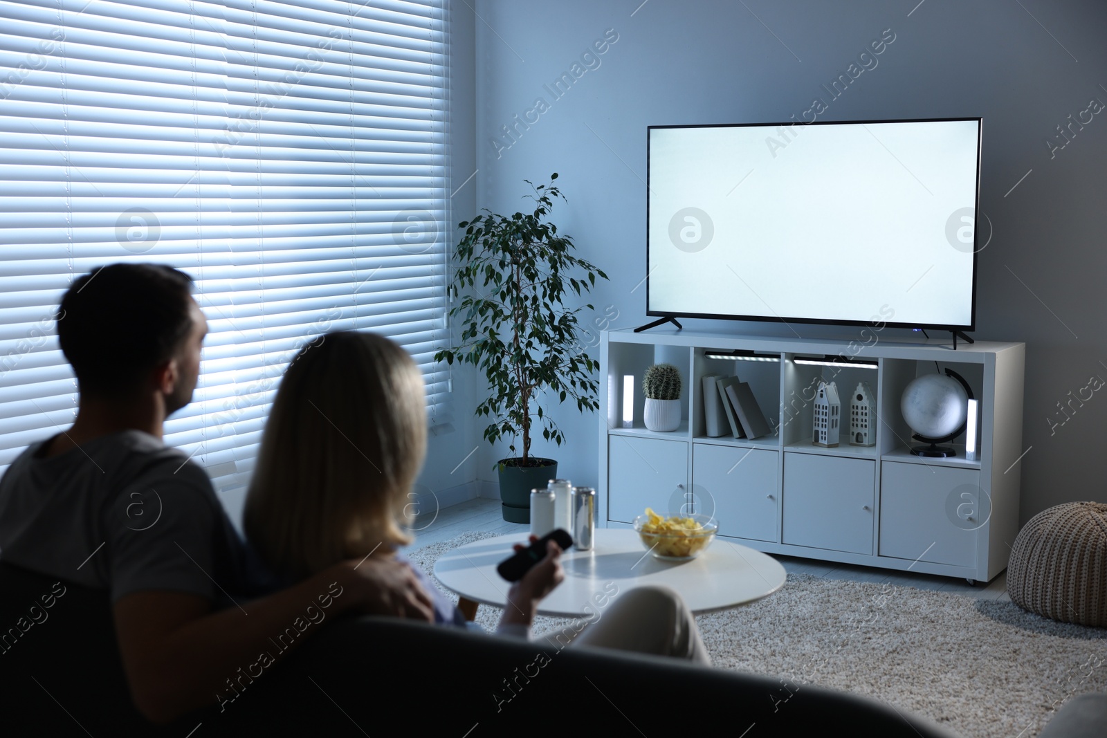 Photo of Lovely couple watching tv on couch at home, back view