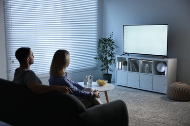 Lovely couple watching tv on couch at home