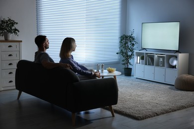 Photo of Lovely couple watching tv on couch at home