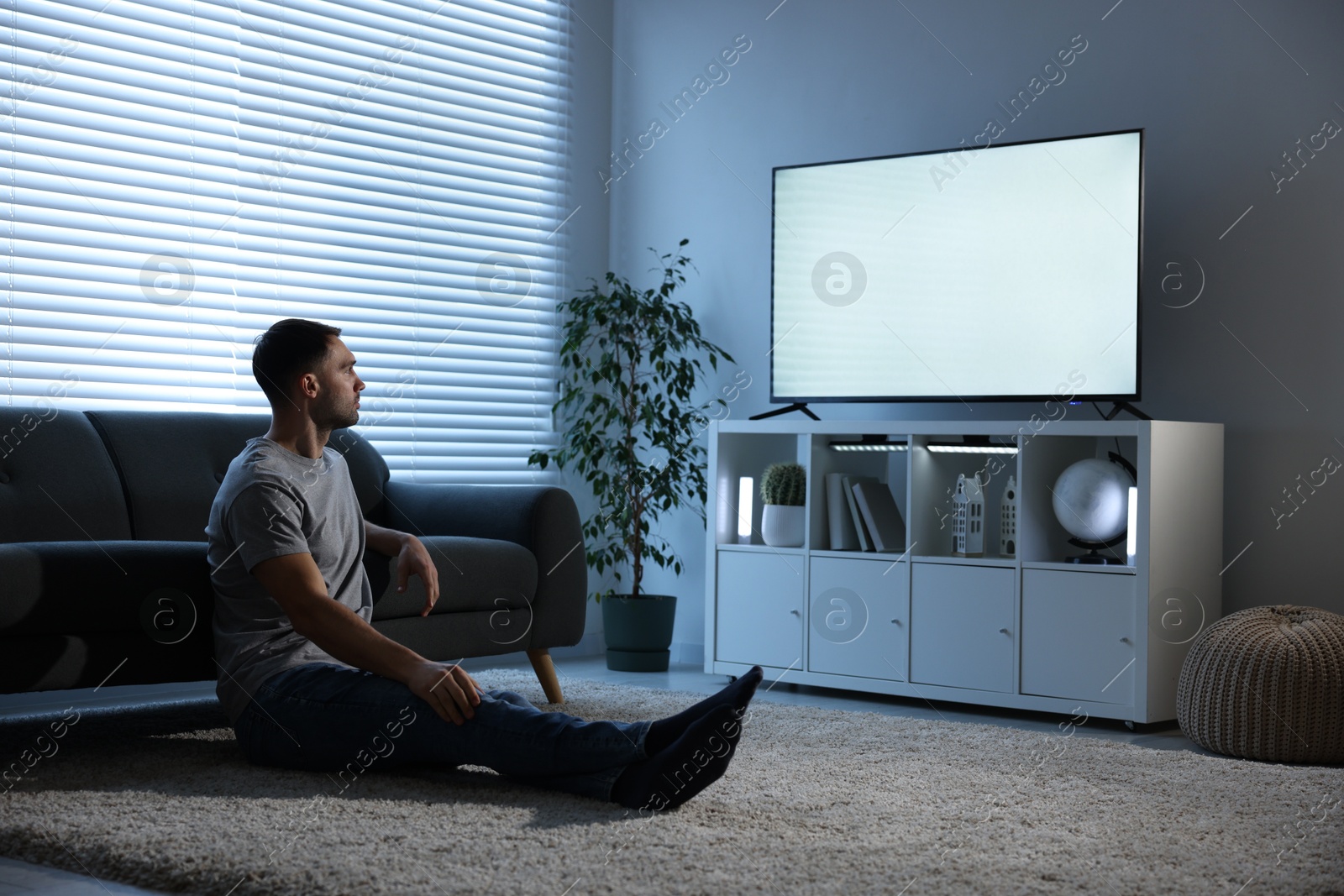 Photo of Man watching tv on floor at home