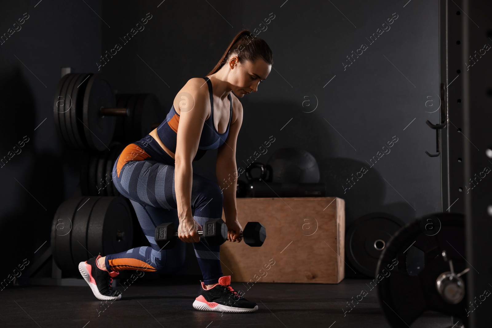 Photo of Sportswoman exercising with dumbbells during crossfit workout in gym. Space for text