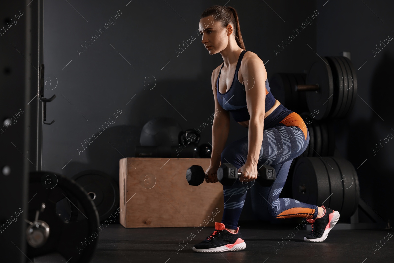 Photo of Sportswoman exercising with dumbbells during crossfit workout in gym. Space for text