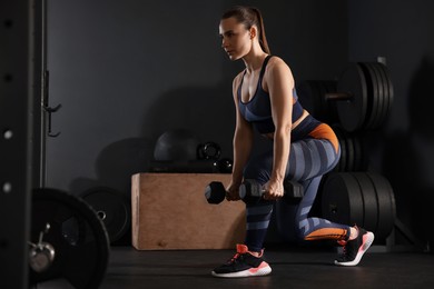 Photo of Sportswoman exercising with dumbbells during crossfit workout in gym. Space for text