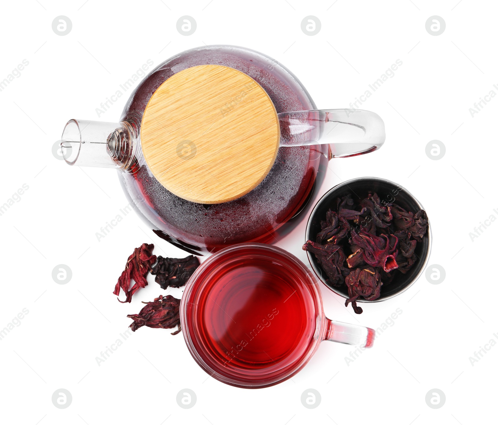 Photo of Delicious hibiscus tea in glass cup, teapot and dry roselle sepals isolated on white, top view