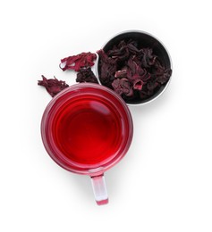 Photo of Delicious hibiscus tea in glass cup and dry roselle sepals isolated on white, top view