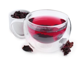 Photo of Delicious hibiscus tea in glass cup and dry roselle sepals isolated on white