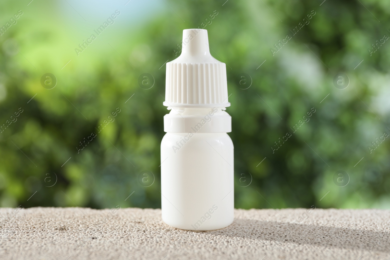 Photo of Allergy treatment. Bottle of medical drops on stone against blurred background, closeup