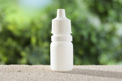 Photo of Allergy treatment. Bottle of medical drops on stone against blurred background, closeup