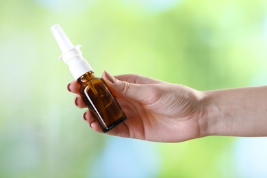 Photo of Allergy treatment. Woman with nasal spray on blurred background, closeup