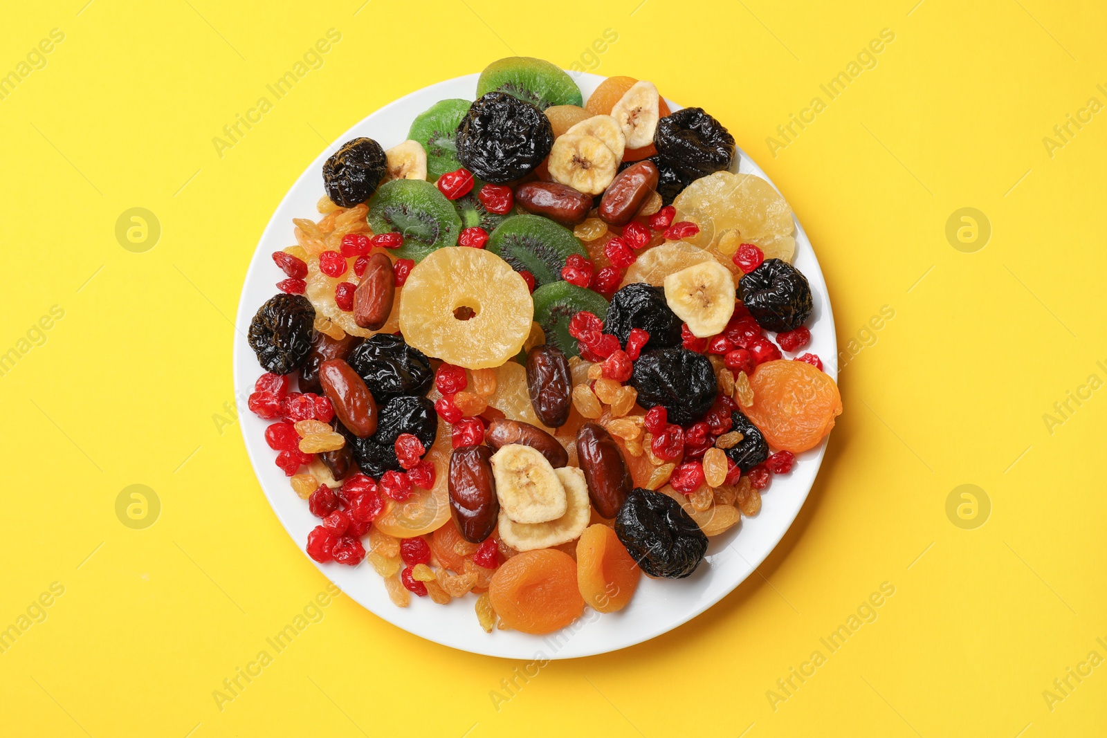 Photo of Mix of different dried fruits on yellow background, top view