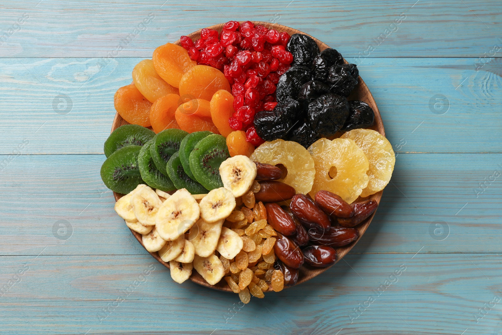 Photo of Different dried fruits on blue wooden table, top view