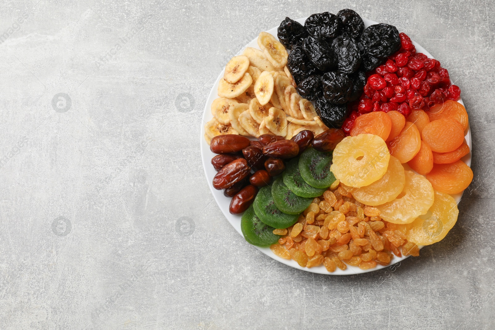 Photo of Mix of different dried fruits on grey table, top view. Space for text