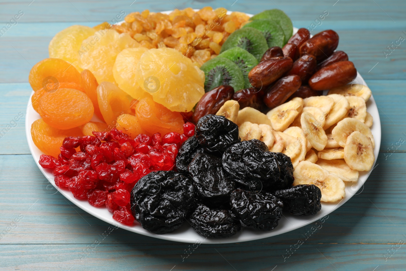 Photo of Mix of different dried fruits on light blue wooden table, closeup