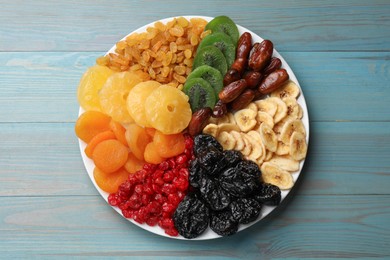 Photo of Mix of different dried fruits on light blue wooden table, top view