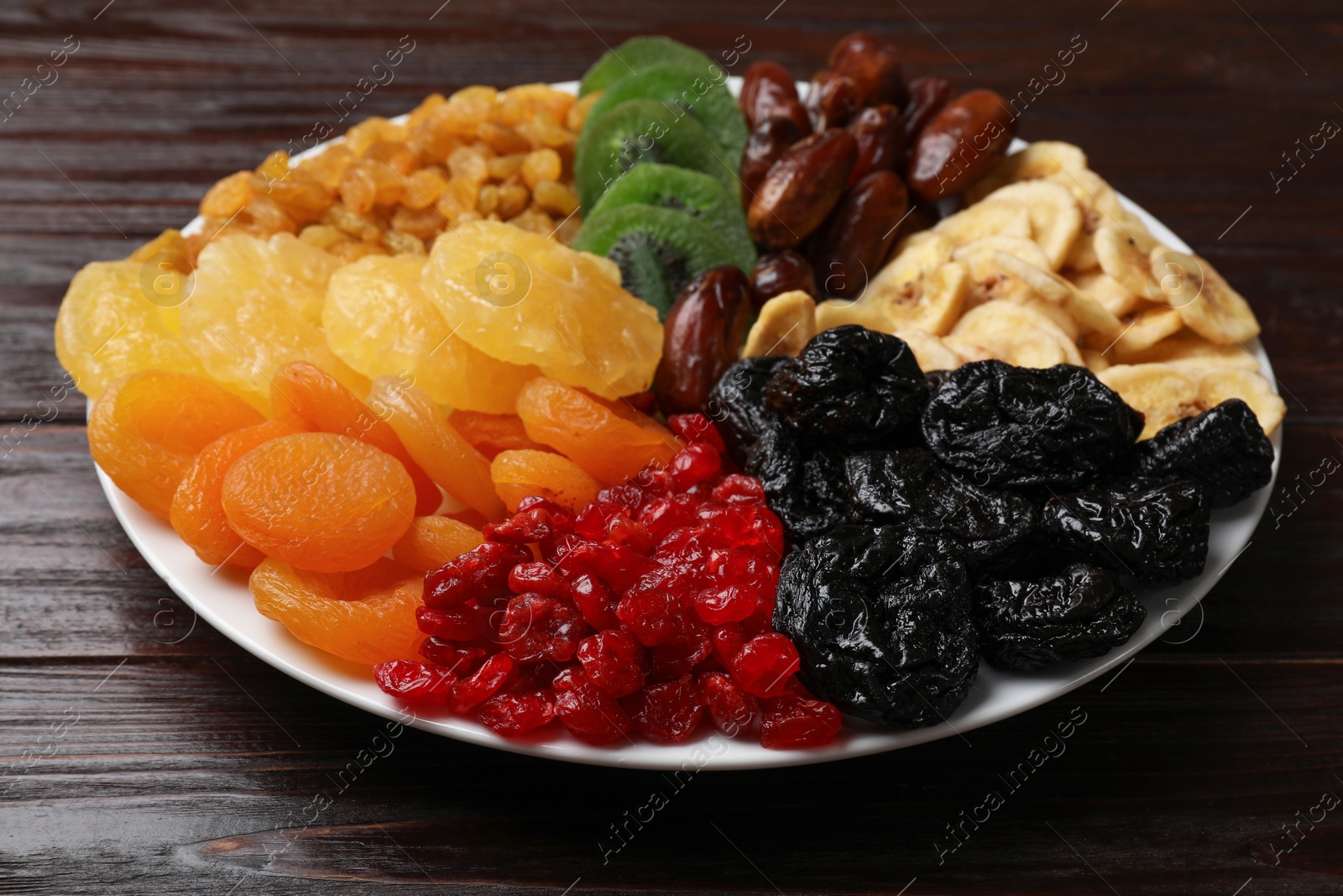 Photo of Mix of different dried fruits on wooden table, closeup