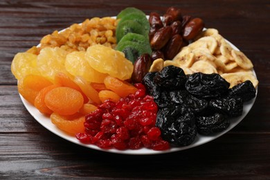 Photo of Mix of different dried fruits on wooden table, closeup