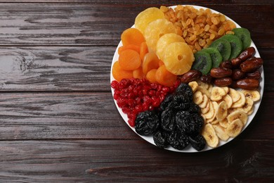 Photo of Mix of different dried fruits on wooden table, top view. Space for text