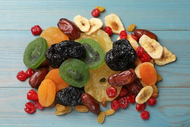 Photo of Mix of different dried fruits on light blue wooden table, top view