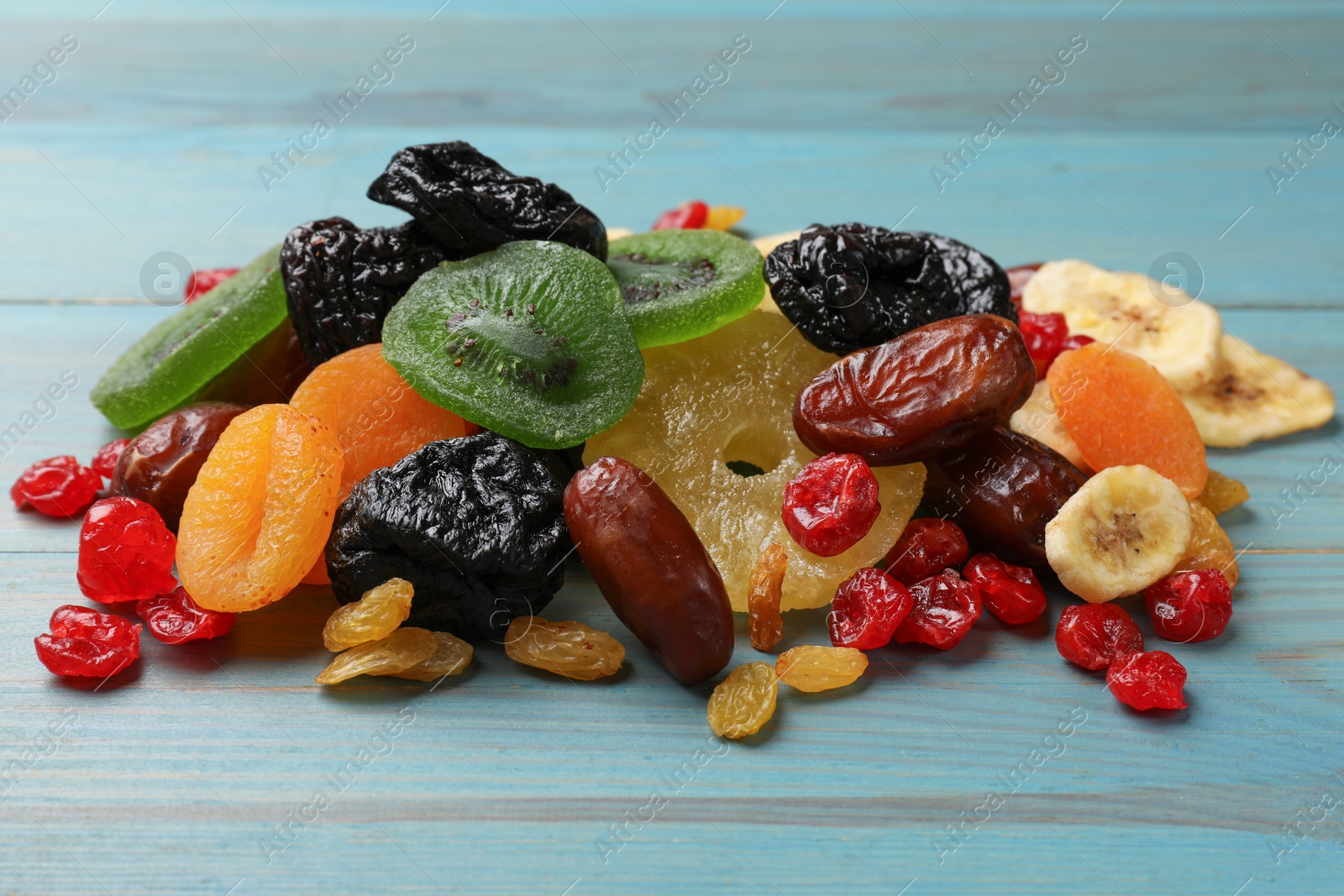 Photo of Mix of different dried fruits on light blue wooden table, closeup