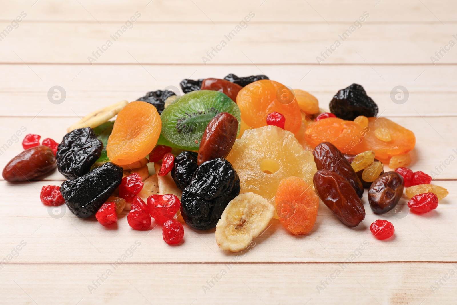 Photo of Mix of different dried fruits on wooden table, closeup