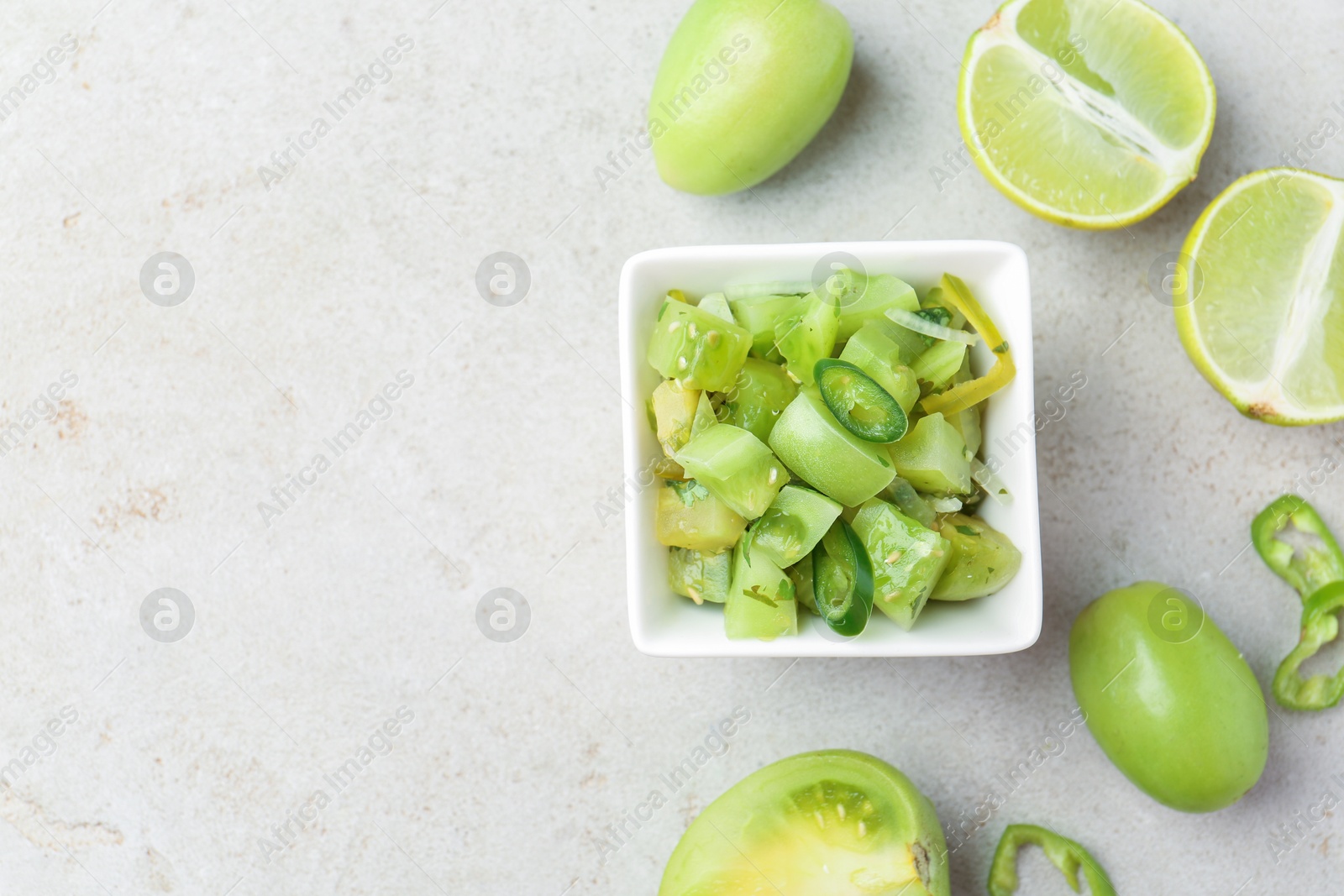 Photo of Delicious salsa (Pico de gallo) in bowl and products on light textured table, flat lay. Space for text