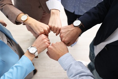 Photo of Teamwork. Group of people joining fists together indoors, above view