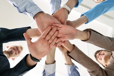 Photo of Teamwork. Group of people joining hands together indoors, bottom view