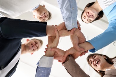 Teamwork. Group of people holding hands together indoors, bottom view