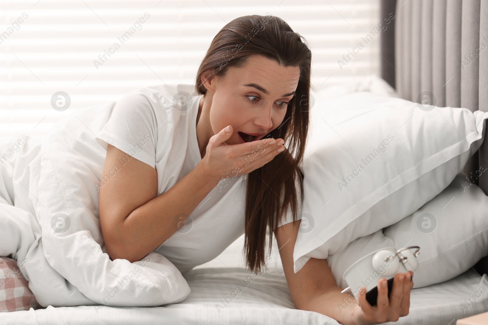 Photo of Overslept woman with alarm clock in bed at home