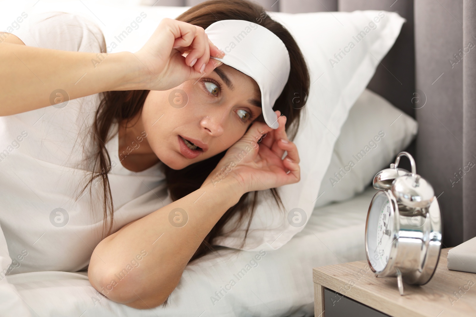 Photo of Overslept woman with alarm clock in bed at home