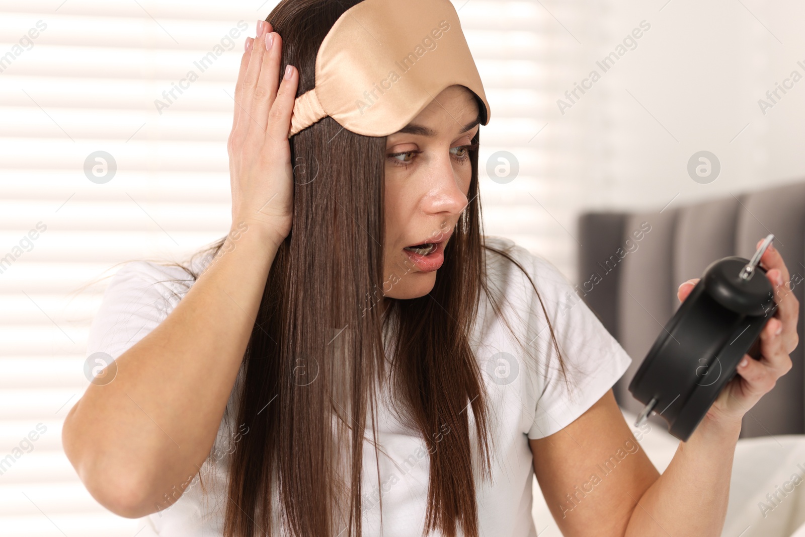 Photo of Overslept woman with alarm clock in bed at home