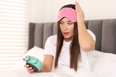 Photo of Overslept woman with alarm clock in bed at home