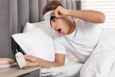 Photo of Overslept man with alarm clock in bed at home