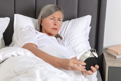 Photo of Overslept woman with alarm clock in bed at home