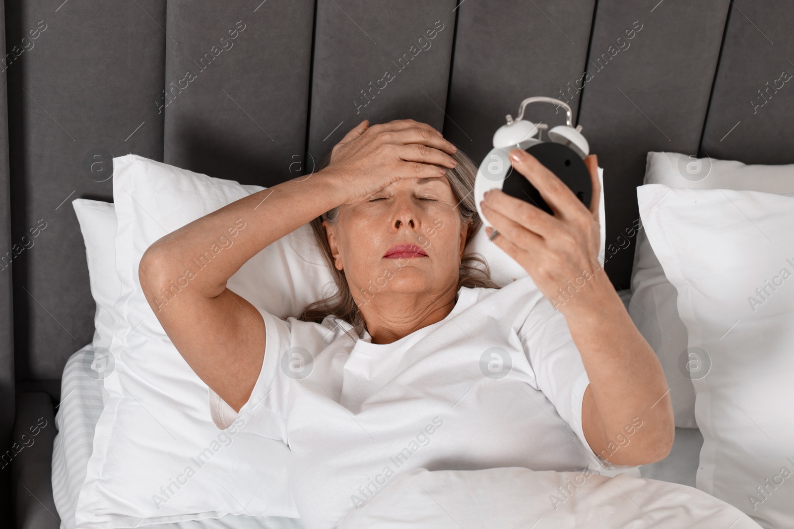 Photo of Overslept woman with alarm clock in bed at home